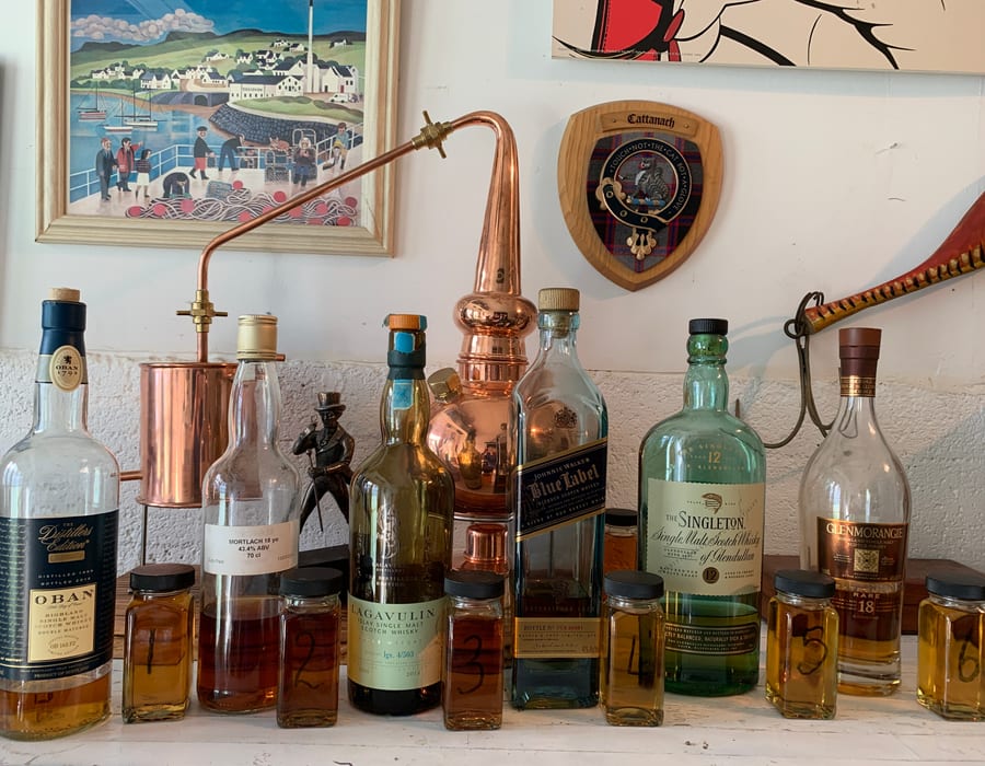 Whisky education setup with numbered samples, bottles and a miniature copper still